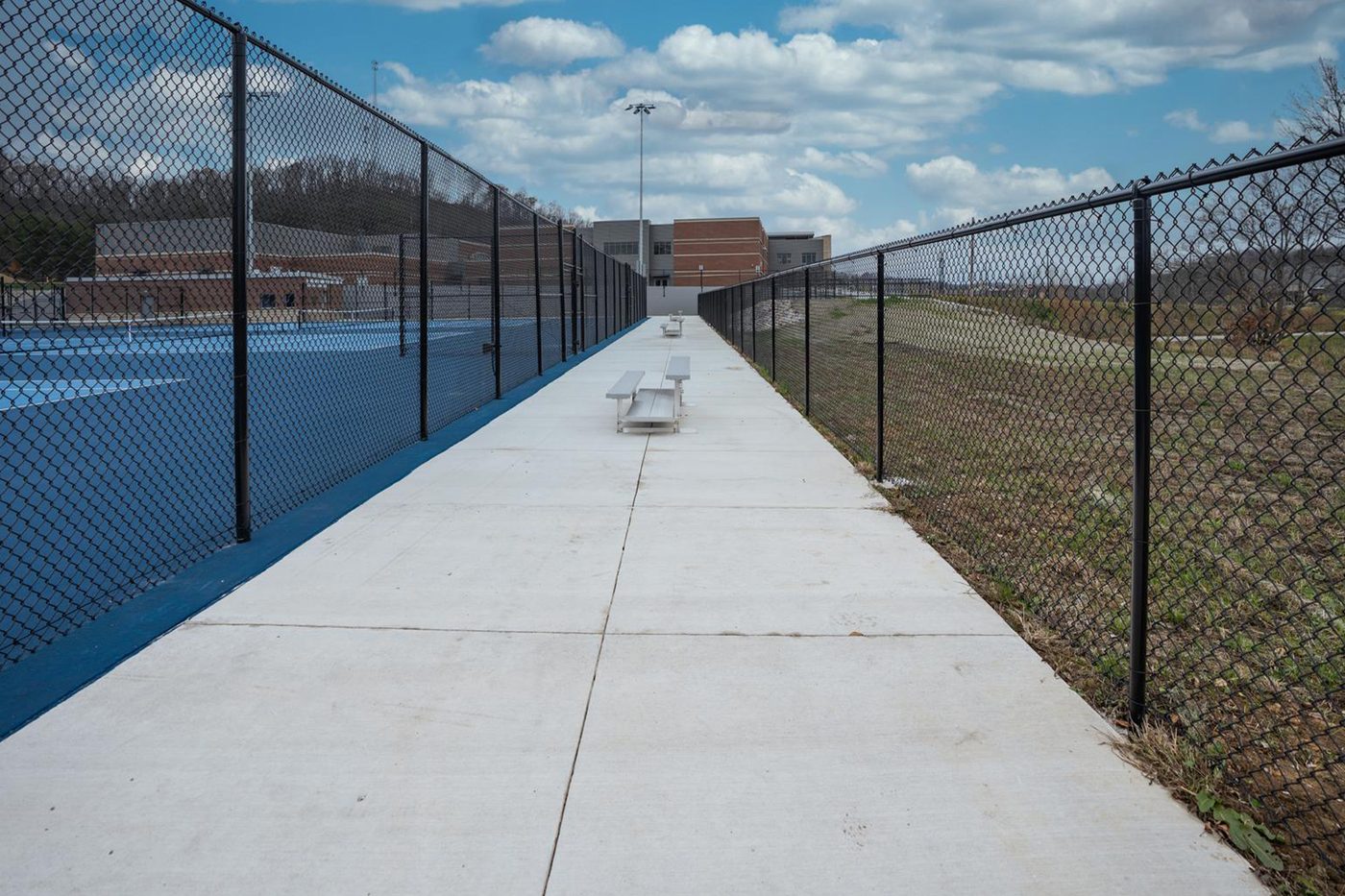 Accessible walkway running alongside the fenced courts