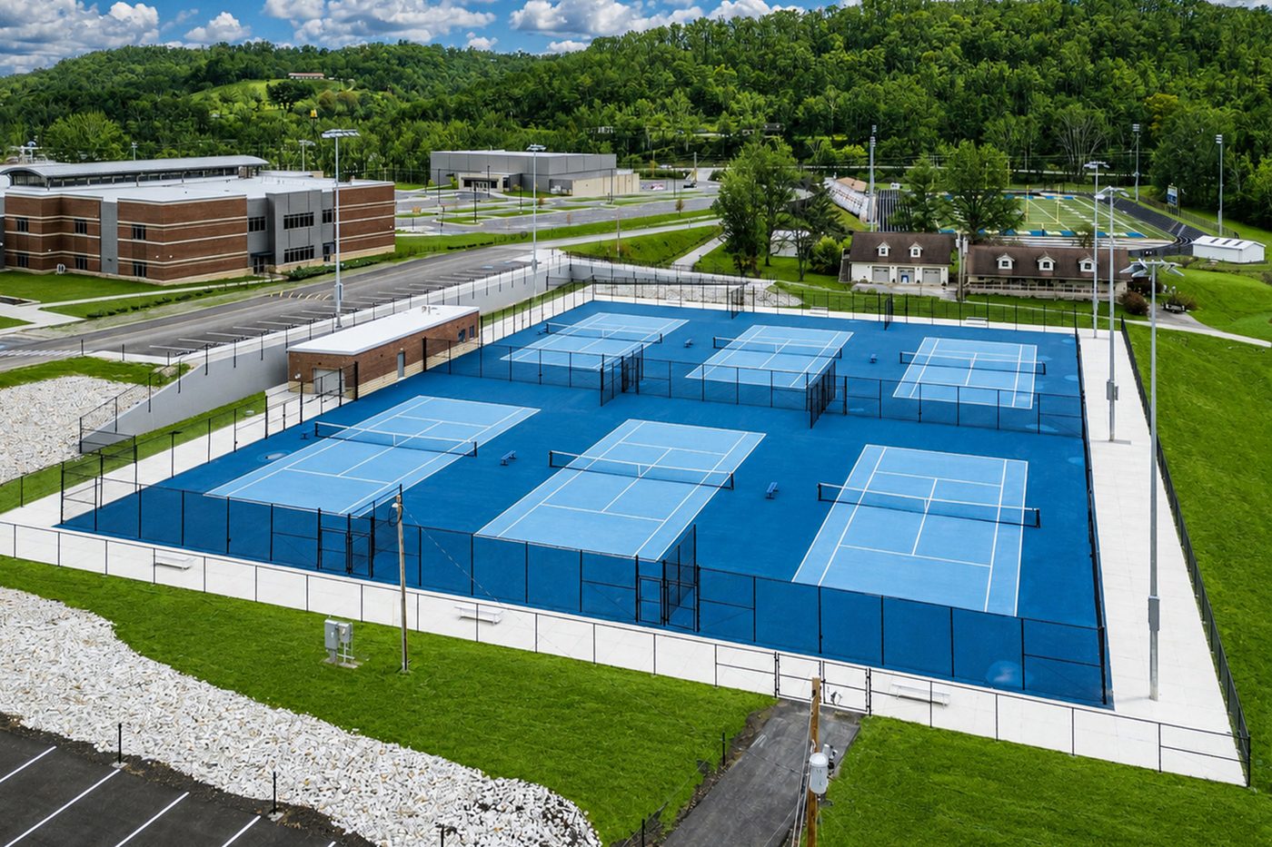 Aerial of the tennis complex framed by wooded hills